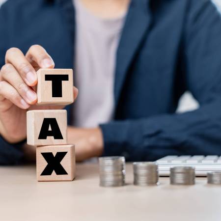 A Wooden blocks spelling tax with coins and calculator on table